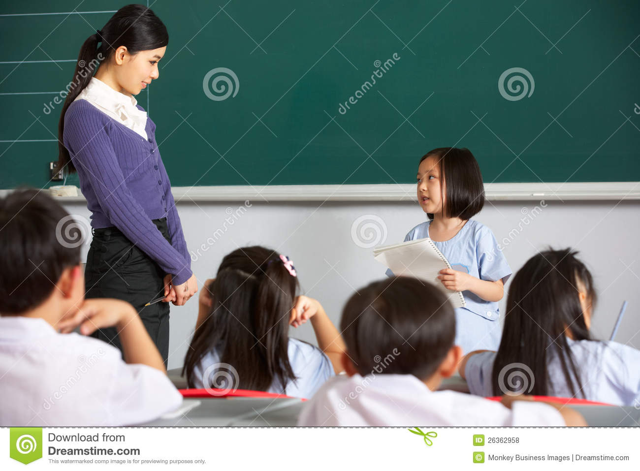 By Blackboard In Chinese School Classroom Looking At Each Other