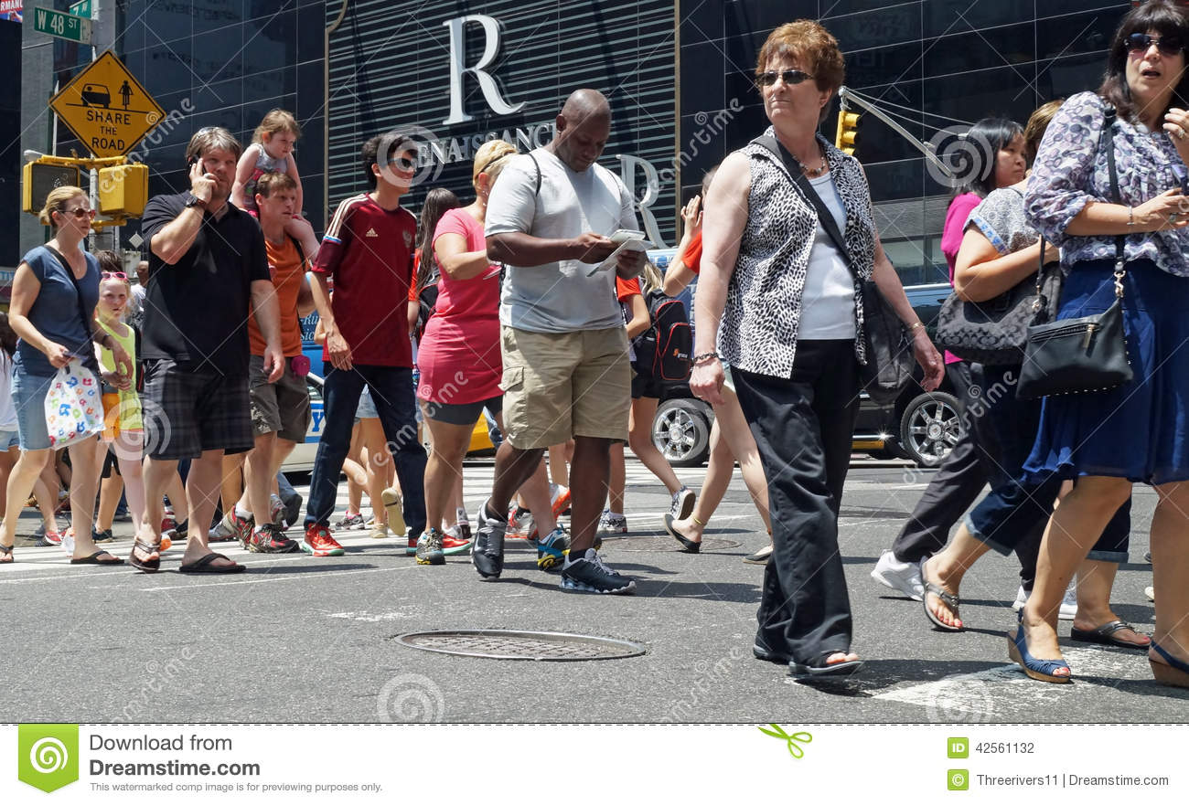    Phones Are Among A Diverse Crowd Of People Crossing A Busy Street In