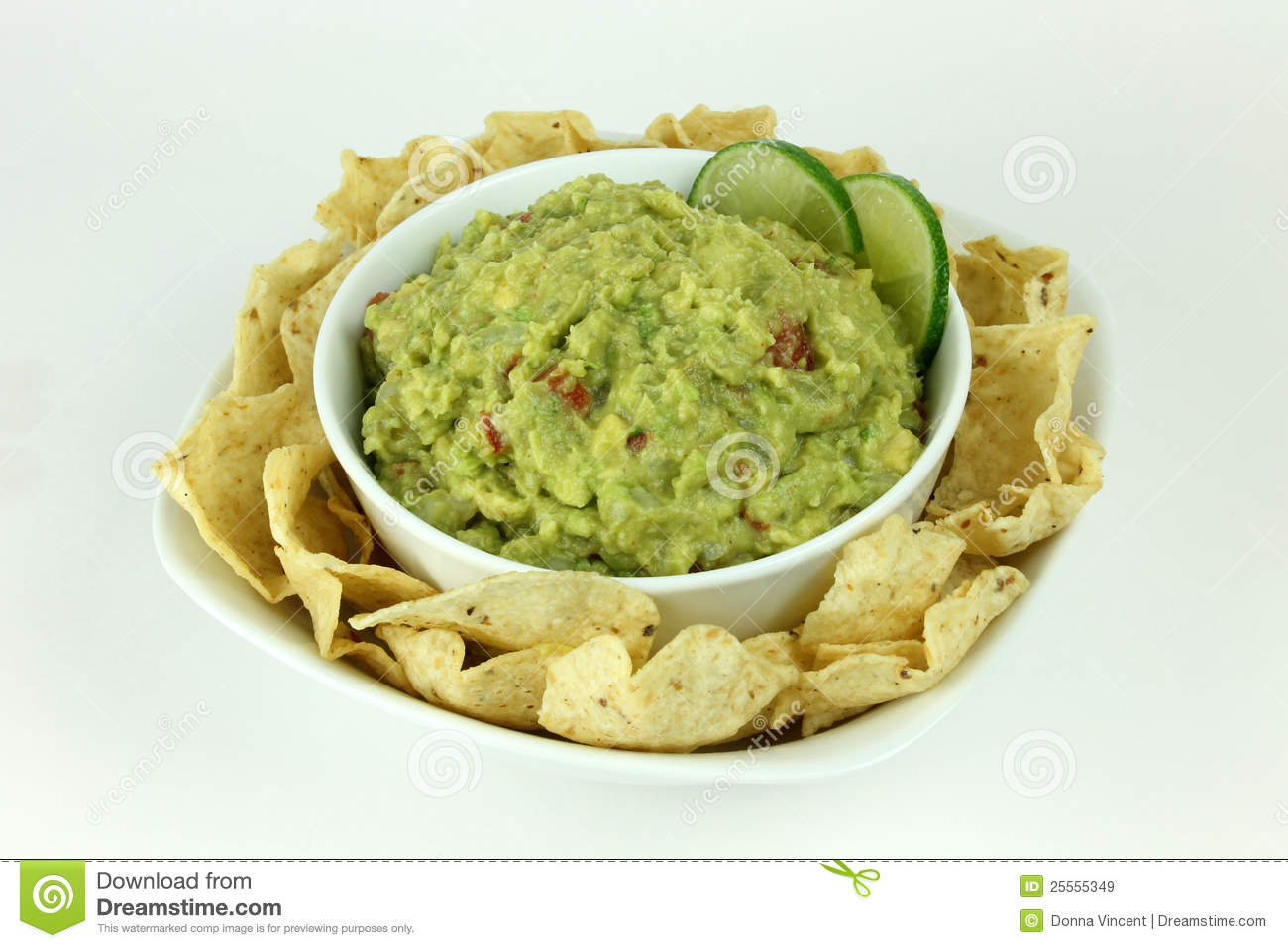 Bowl Of Guacamole With Lime Slices On A Plate Of Tortilla Chips On An