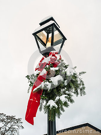 Lamp Post With Christmas Decoration Of Red Ribbon And Evergreen Bough