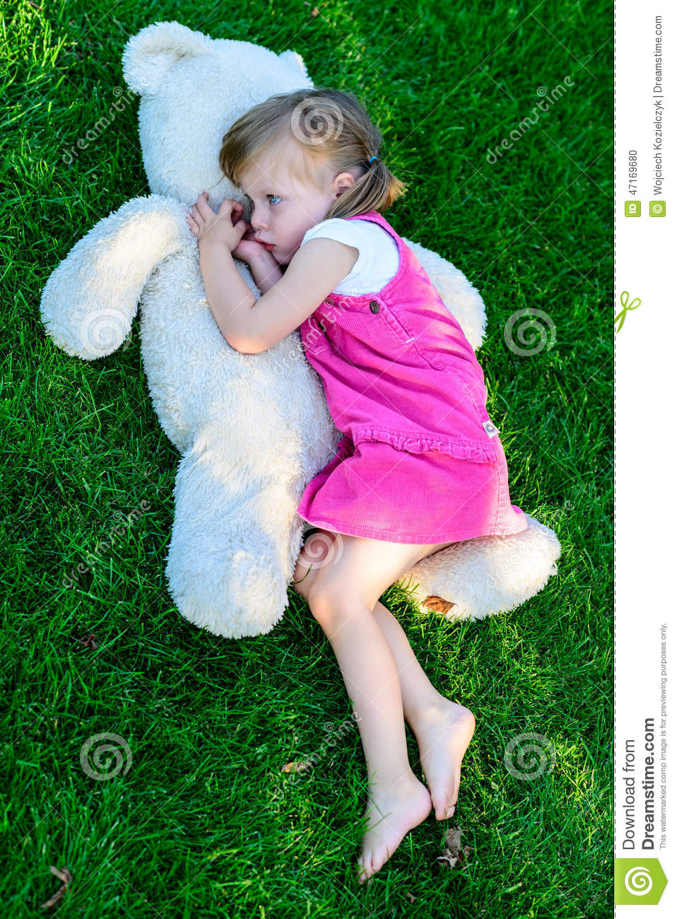 Sad Little Girl Lying On Grass With Large Teddy Bear  Upset Child