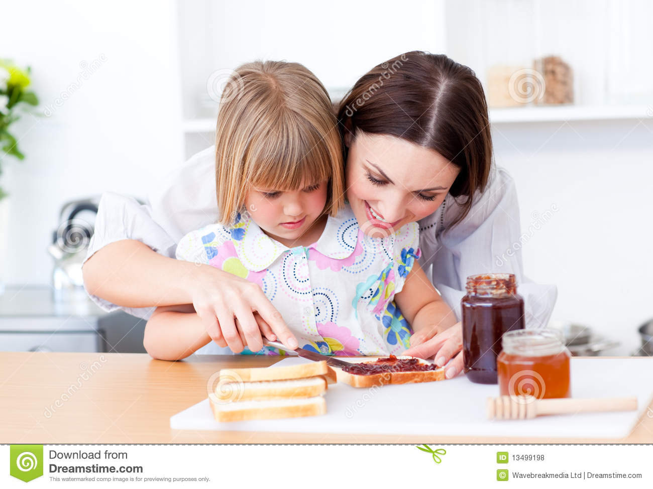 Brunette Mother And Her Daughter Preparing A Breakfast In The Kitchen