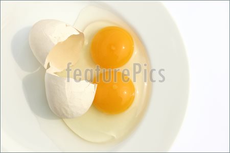 With Two Yellow Yolks On A White Plate Against A White Background