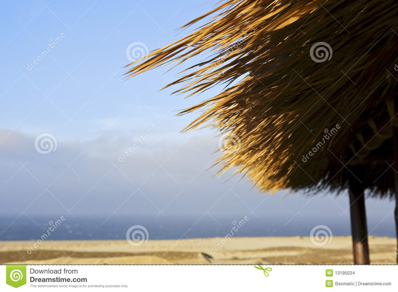 The Roof Of A Grass Hut With An Idyllic Sandy Beach In The Background