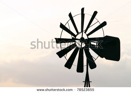 Old Farm Windmill For Pumping Water With Spinning Blades At Sunset In