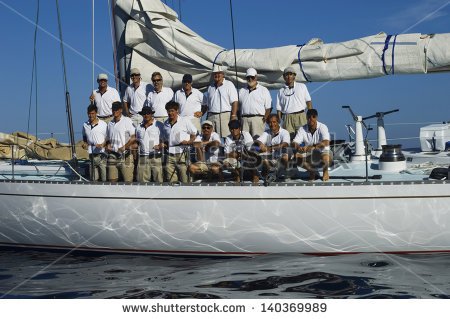 Sailing Crew Posing For A Group Portrait On Board Against Clear Blue    