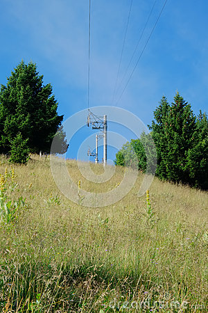 Looking Up At A Ski Lift Track With Wire Towers On A Grassy Mountain