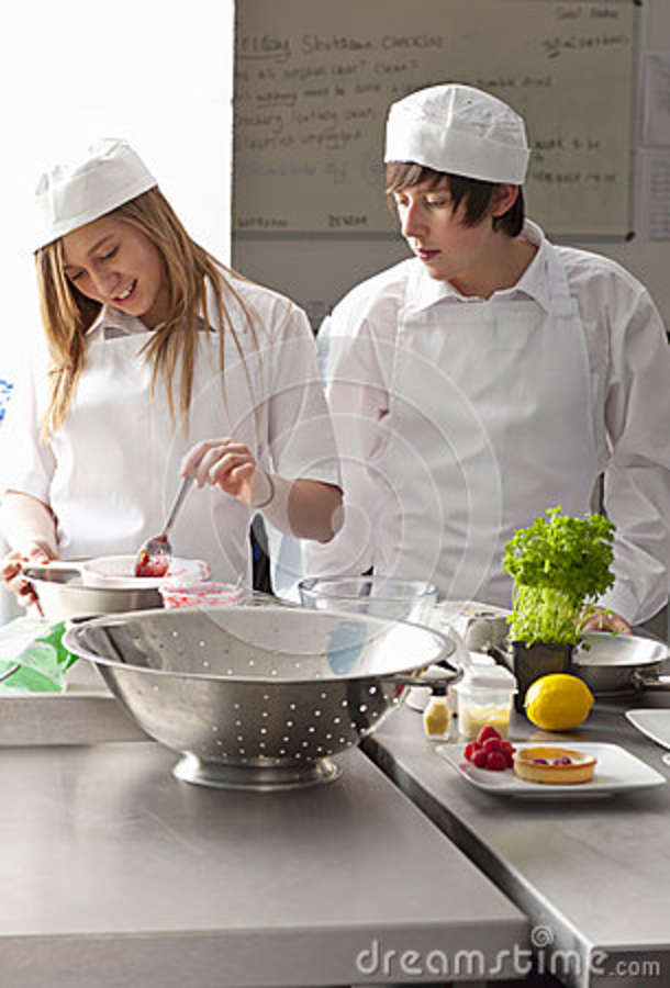 Trainee Chefs Working Together In Commercial Kitchen