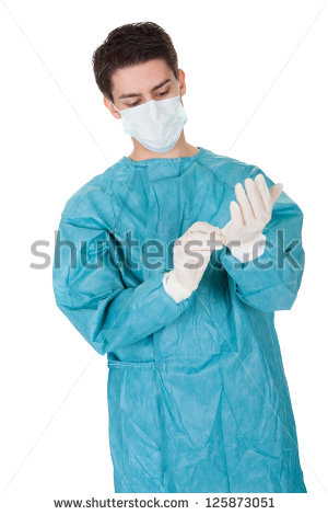 Young Male Surgeon In A Mask And Gown Putting On Disposable Surgical