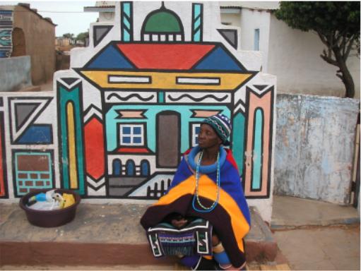 Ndebele Woman Sitting In Front Of Her Wall Painting