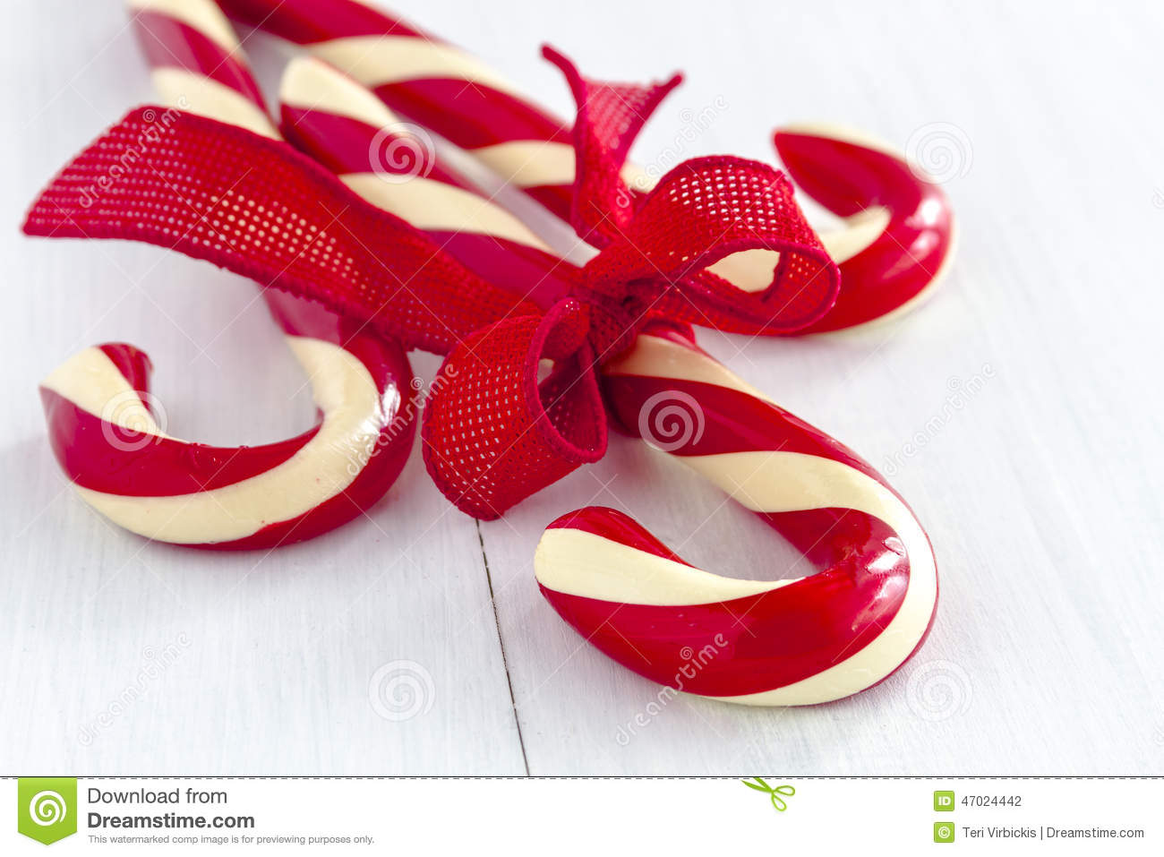     Candy Canes Tied With Red Burlap Ribbon Sitting On White Wooden Table