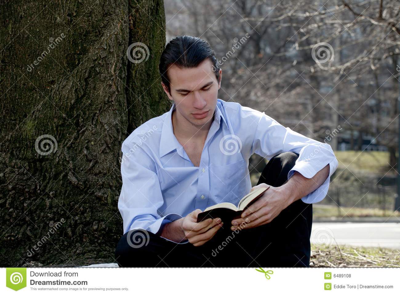 Man Sits In Park Rearding Bible  Photo Taken On A Cool Day In March