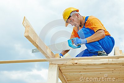 Worker Sawing Wood Board With Hand Saw On Roof Installation Work