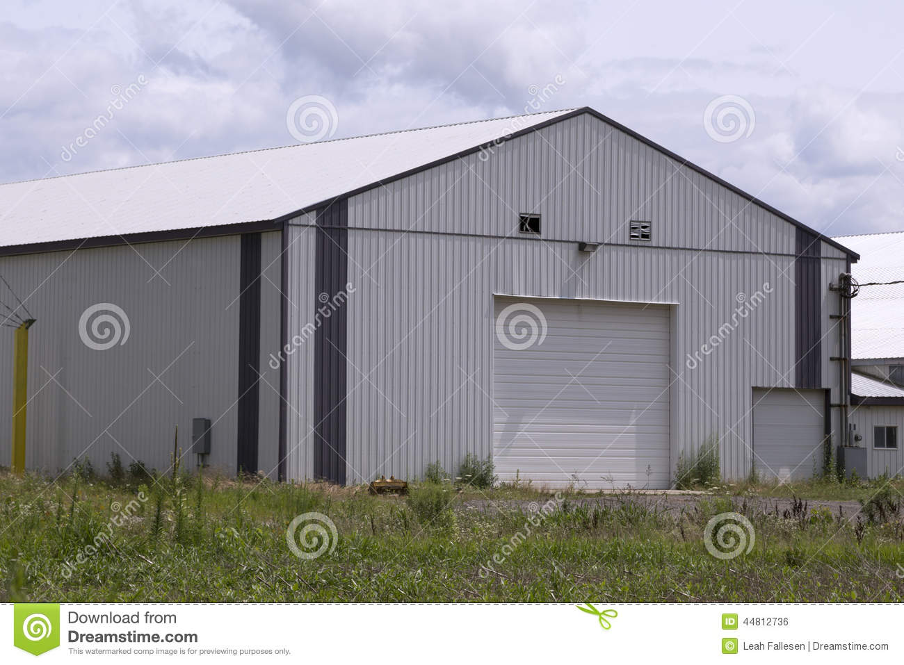 Huge Gray Metal Pole Barn With White Roof And Door  Cloudy Afternoon