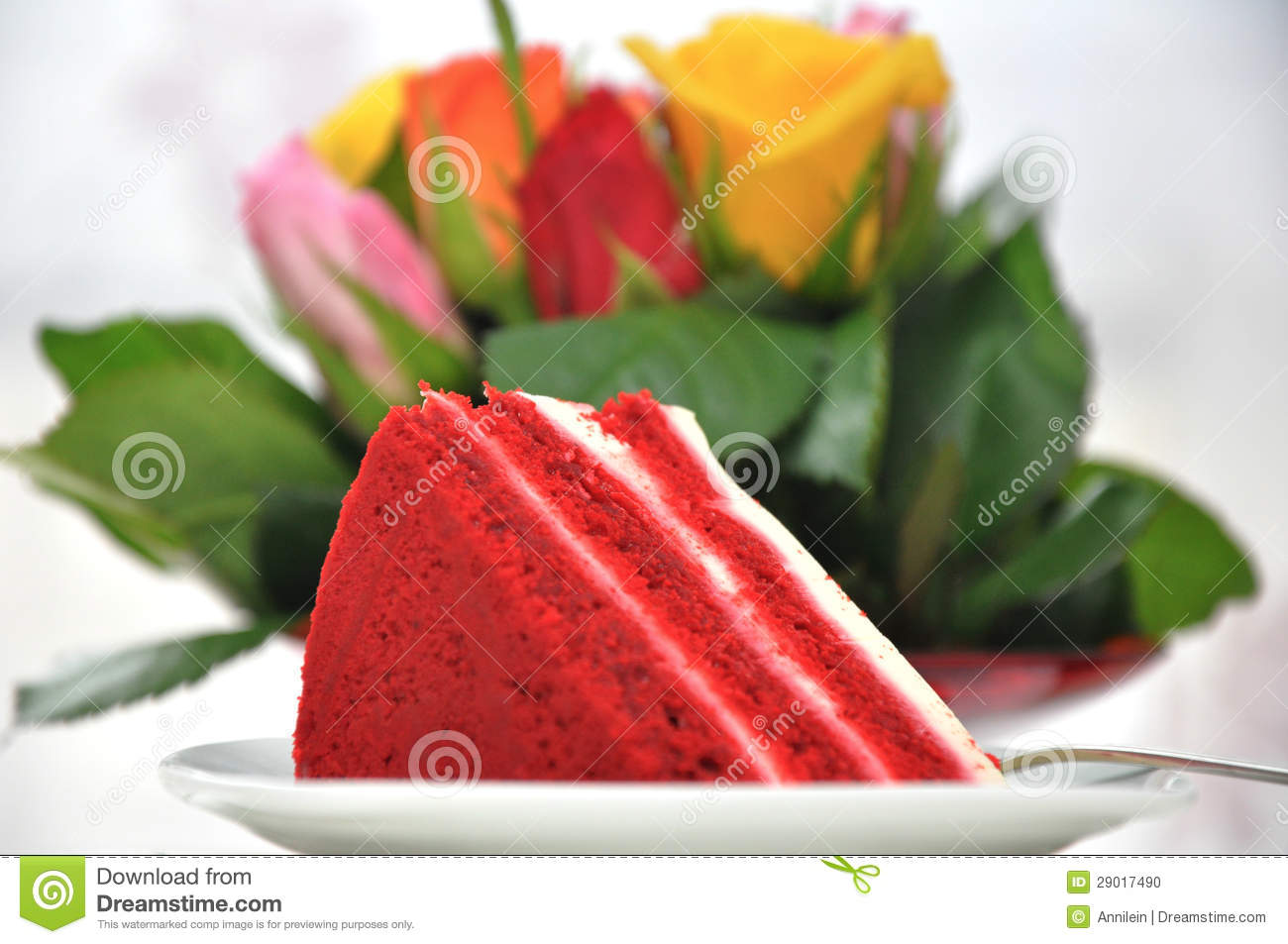 Slice Of Red Velvet Cake On Plate With Roses In The Background