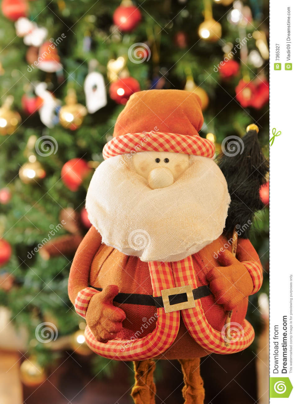 Sweet Rag Santa Doll Looking To The Camera With A Christmas Tree    
