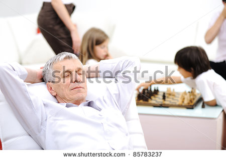 Senior Man On Sofa Taking A Nap Family In Background   Stock Photo    