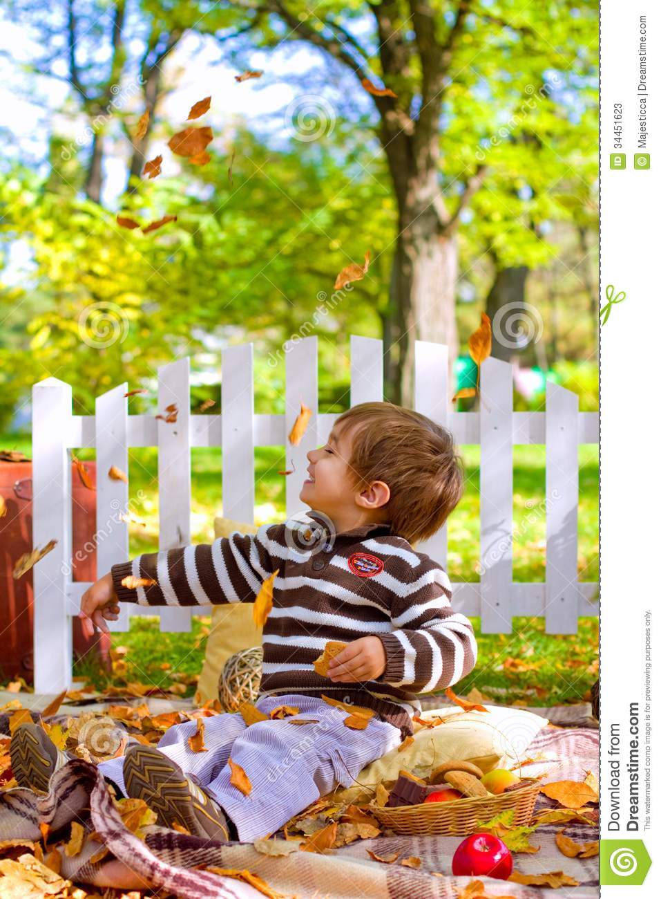 Little Boy Playing With Leaves And Eating Cookies In The Autumn Stock