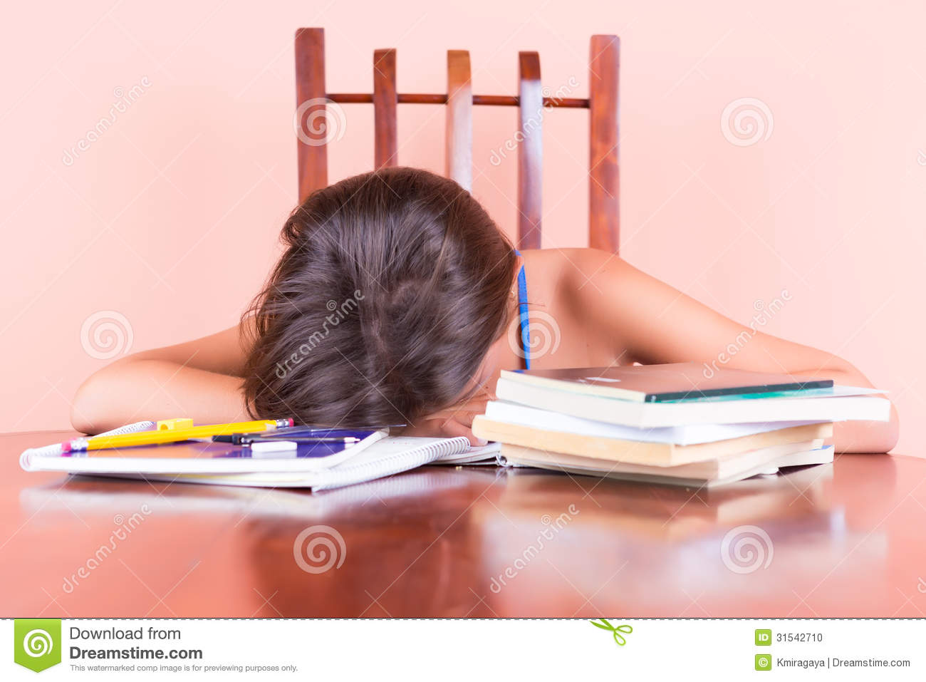 Exhausted Student Sleeping With Her Head On A Table And Books By Her