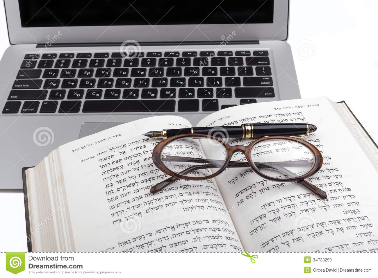 Old Hebrew Bible With Glases A Pen And Silver Laptop In The Background    