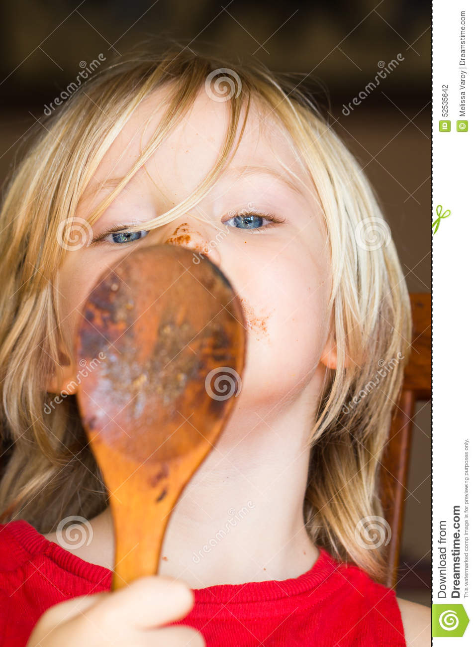 Cute Child With A Messy Face Licking Chocolate Off A Wooden Spoon