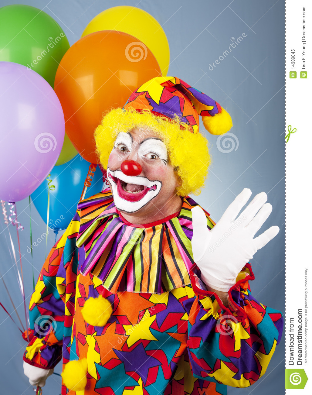 Friendly Circus Clown Holding A Bunch Of Balloons And Waving Hello