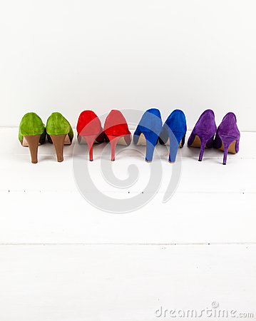 Row Of Colourful Suede Stiletto Shoes On A White Floor Infront Of A    
