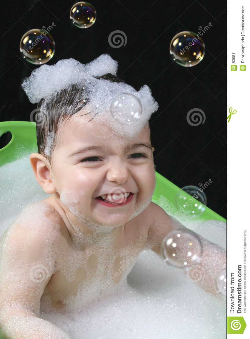 Two Year Old Boy In A Green Tub Of Bubble Water With Bubbles On His