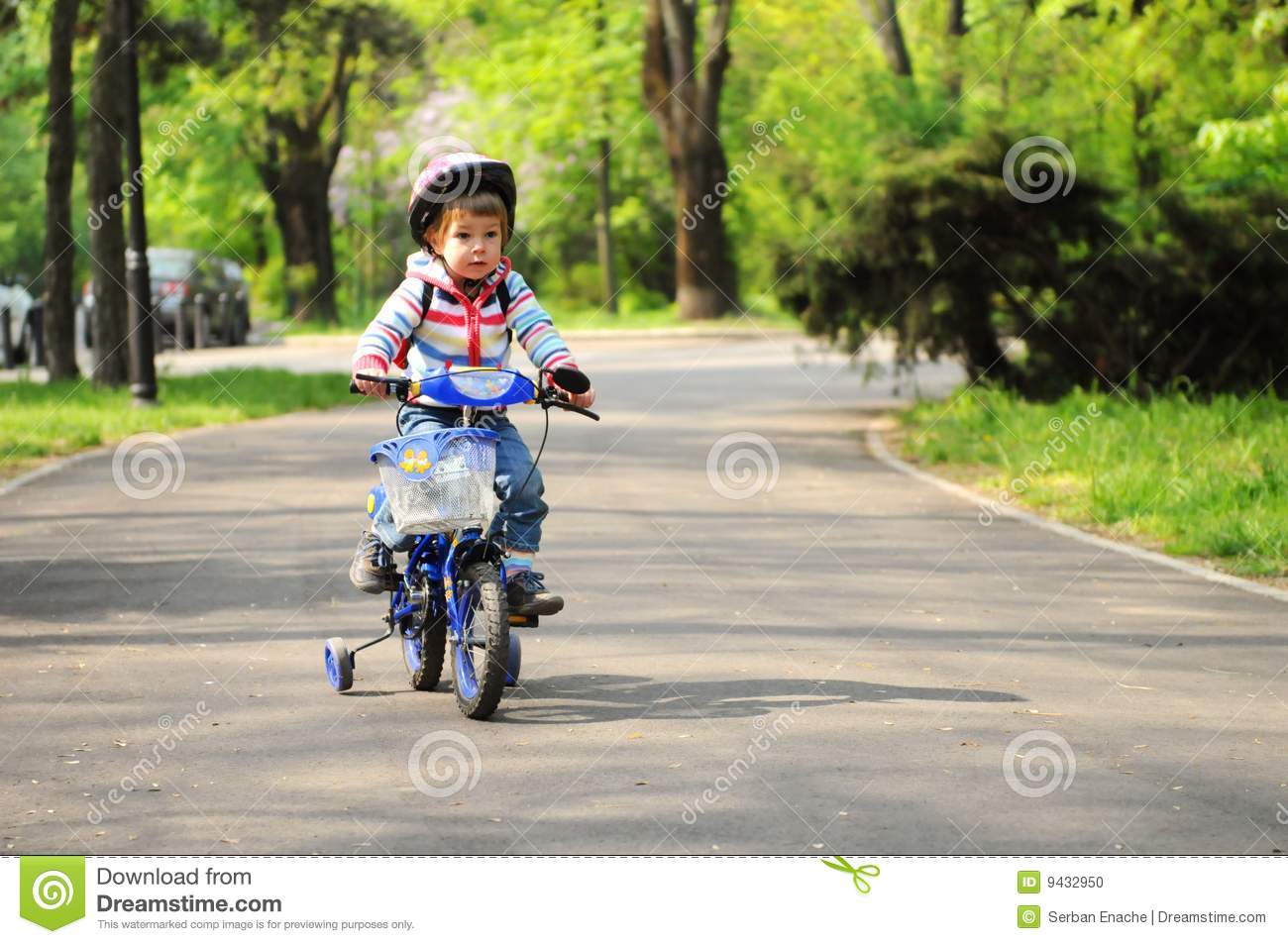 Little Girl Learning To Ride A Bicycle With Training Wheels