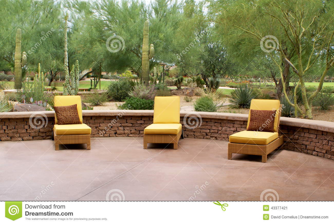 Three Modern Yellow Lounge Chairs On A Patio Surrounded By Greenery