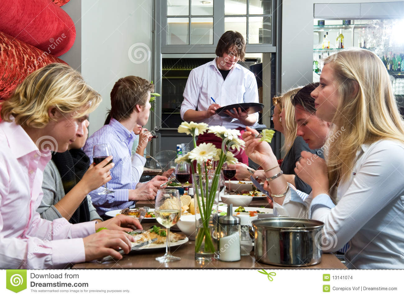 Waiter Taking Orders From A Group Of Dinner Guests At A Restaurant