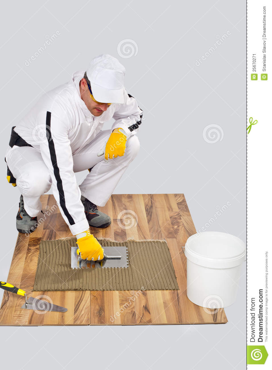 Construction Worker In White Coveralls Applying Tile Adhesive With