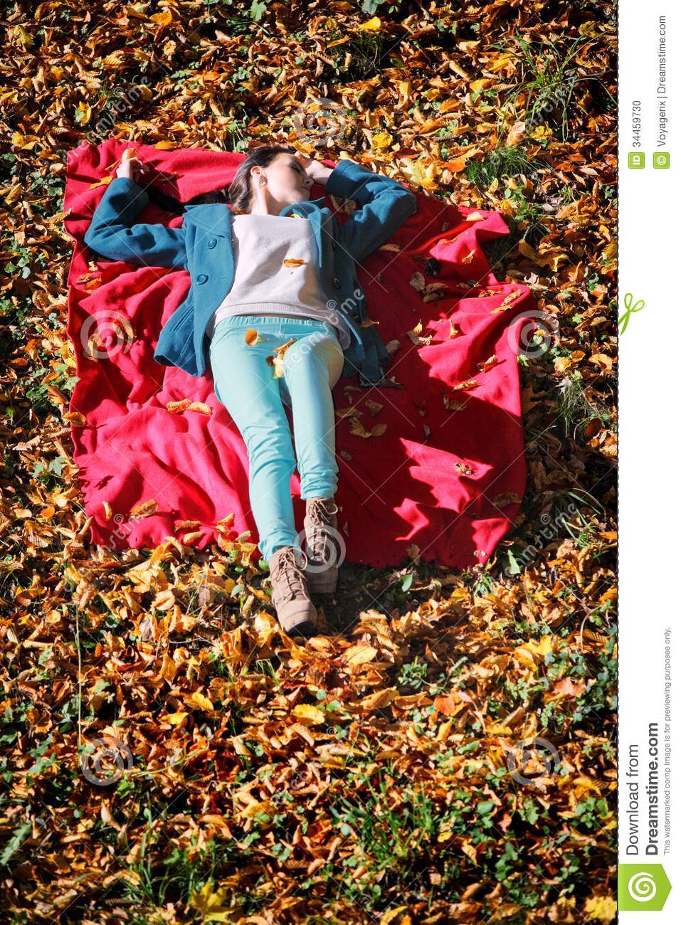 Young Girl Relaxing In Autumnal Park Lying On Red Blanket Stock Photo