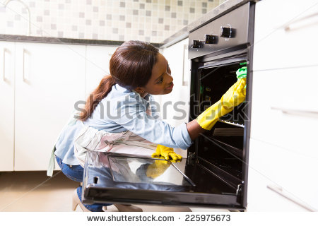 African Woman Cleaning Stove In The Modern Kitchen   Stock Photo