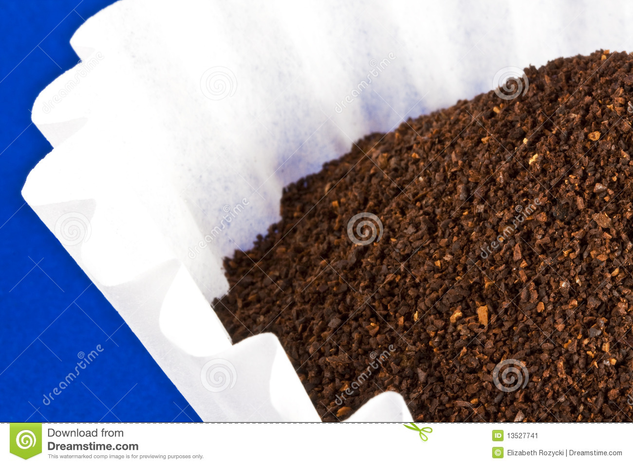 Pile Of Coffee Grounds Sits In A White Filter On Top Of Blue