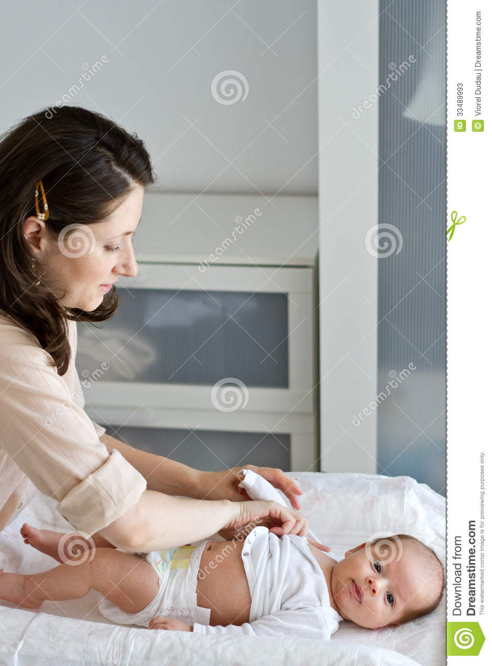 Nurse Dressing The Newborn Baby In The Nursery 