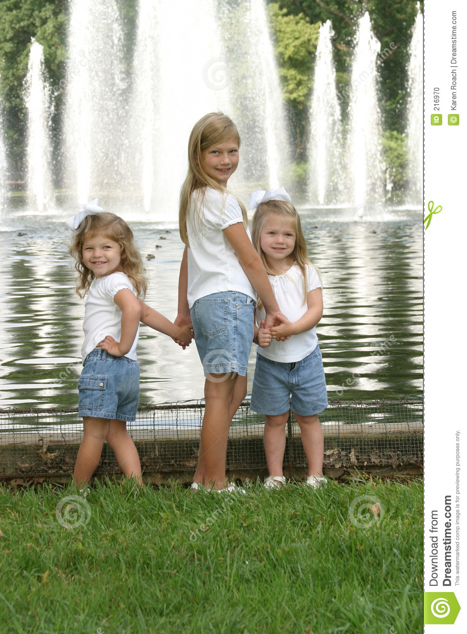 Three Sisters Holding Hands In Front Of A Fountain 