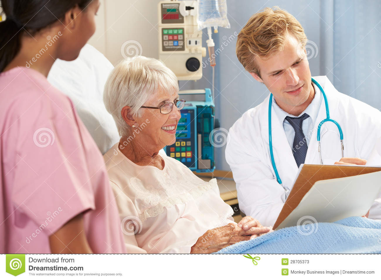 Doctor With Nurse Talking To Senior Female Patient In Bed Stock Photos