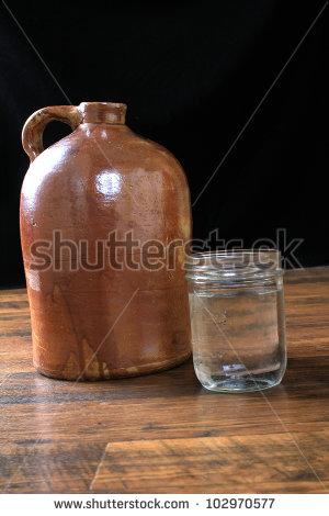 Fruit Jar Full Of Moonshine Whiskey Poured From Old Brown Jug On
