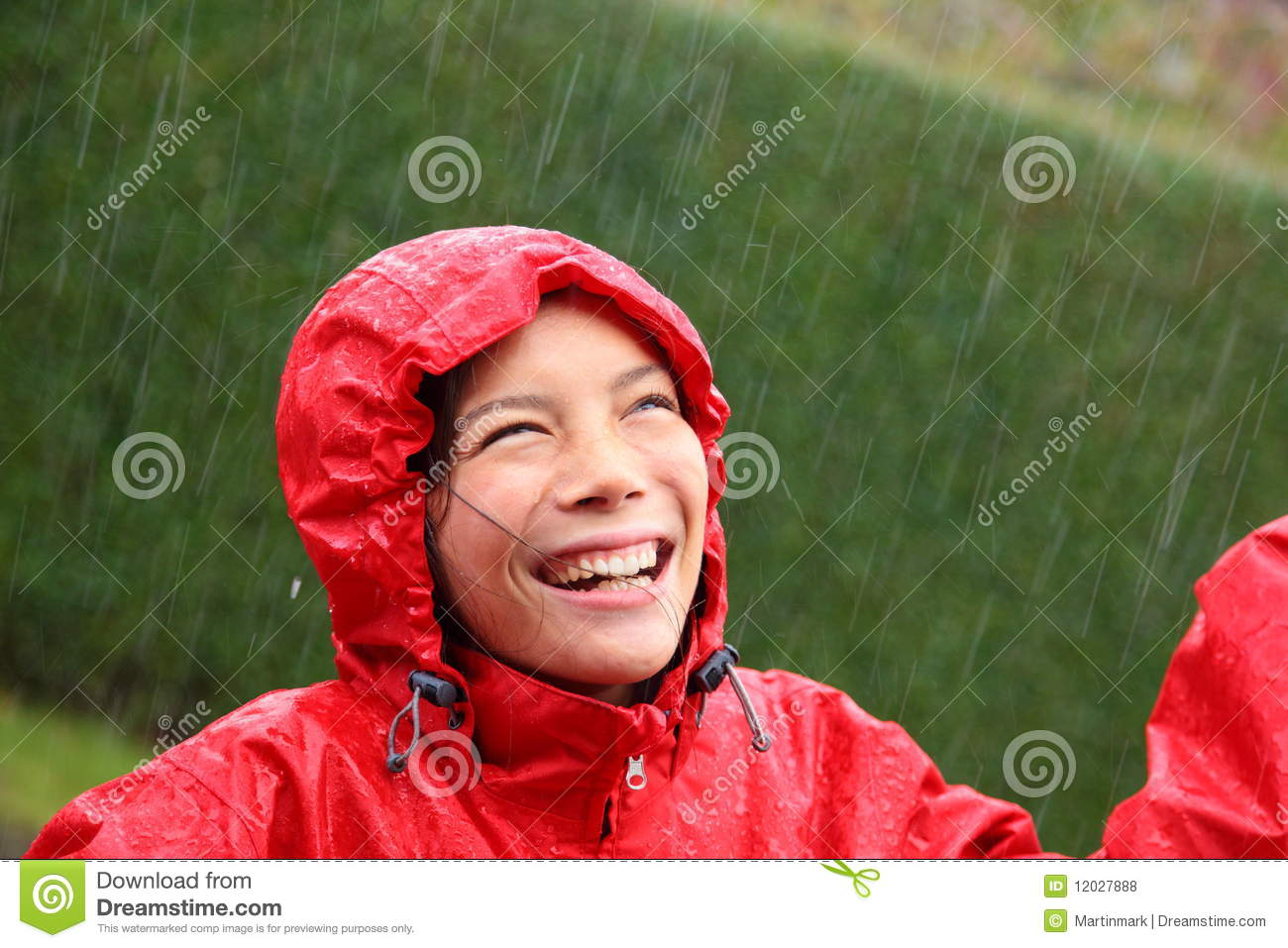Young Woman Wearing A Red Raincoat Enjoying The Rain And Having Fun