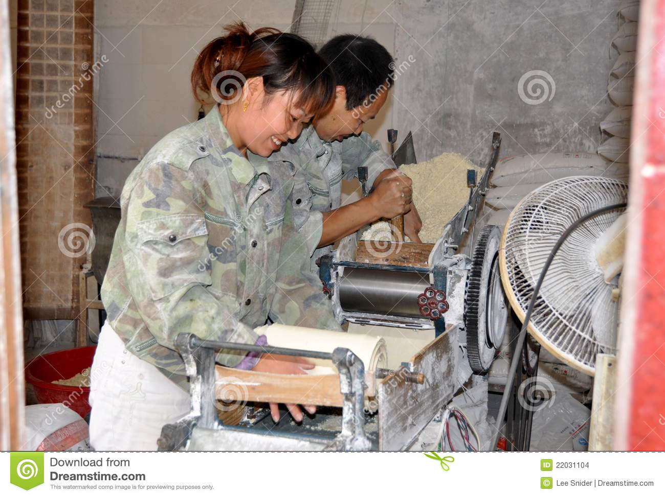 Husband And Wife Using An Intricate Machine Making Noodle Dough From A