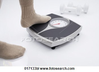 Detail Of Person Stepping On Scales With Dumb Bells In Background View