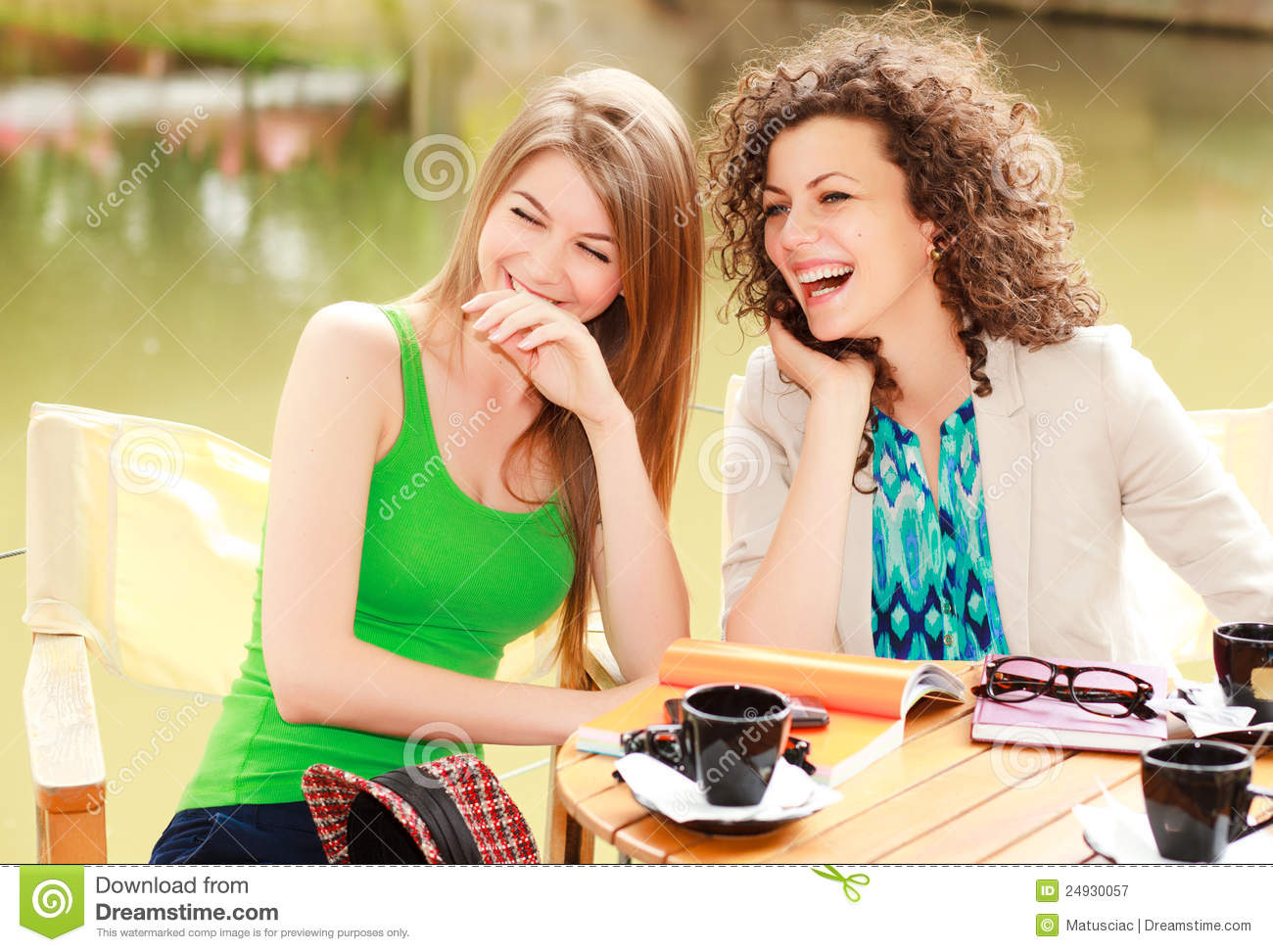 Two Beautiful Women Laughing Over A Cofee At The River Side Terrace    