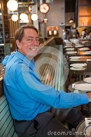 Caucasian Male Sitting At A Restaurant Smiling