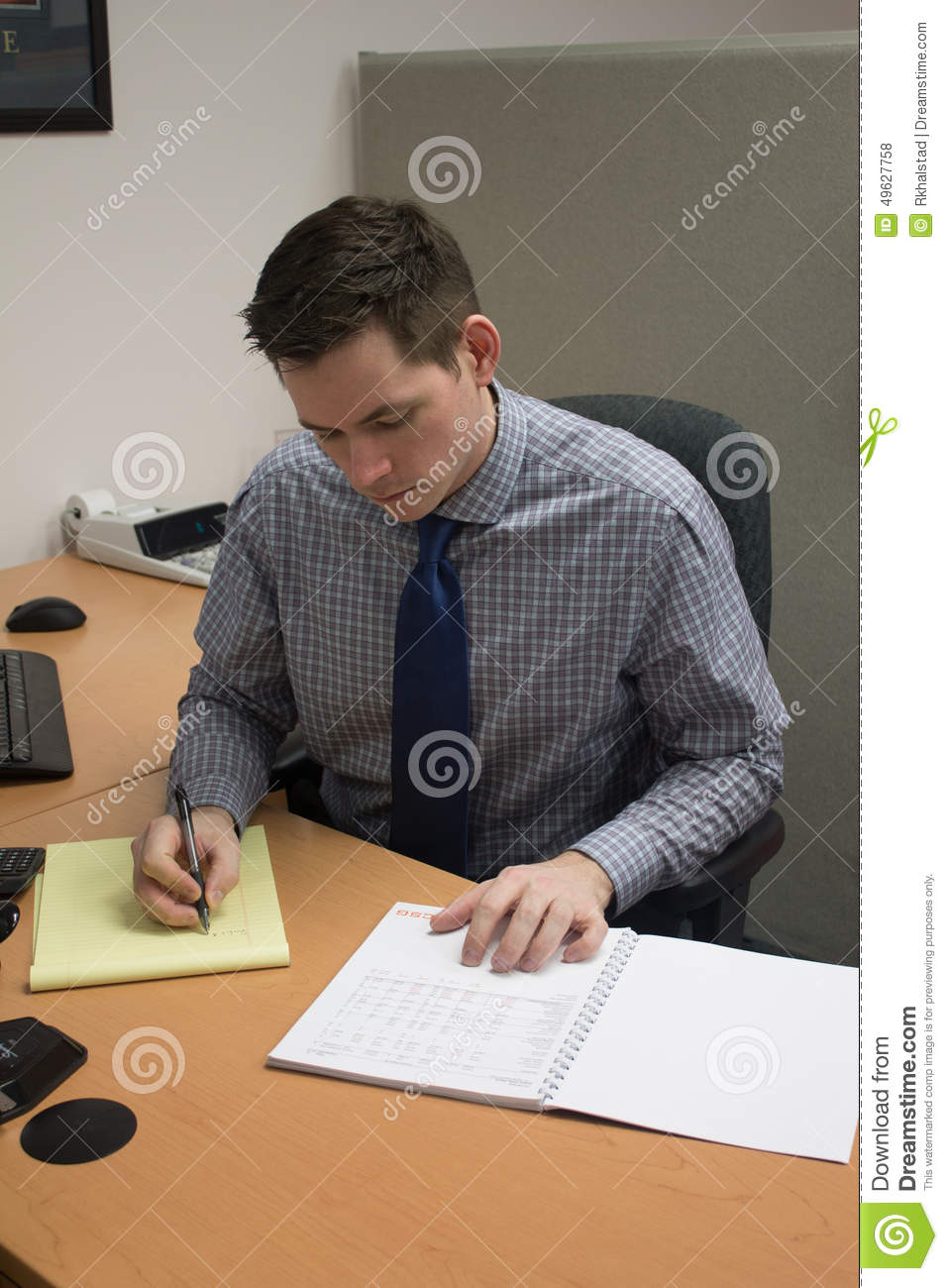 Man Writing Notes At His Desk In An Accounting Office Vertical View