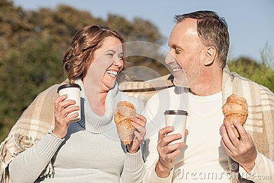 Pretty Senior Husband And Wife Are Eating Croissants In Park  They Are