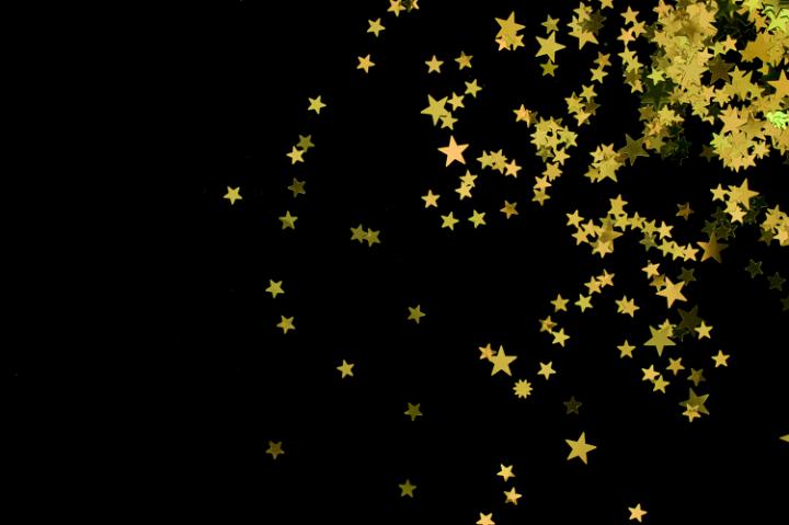 Scattering Of Yellow Coloured Glitter Star Shapes On A Black