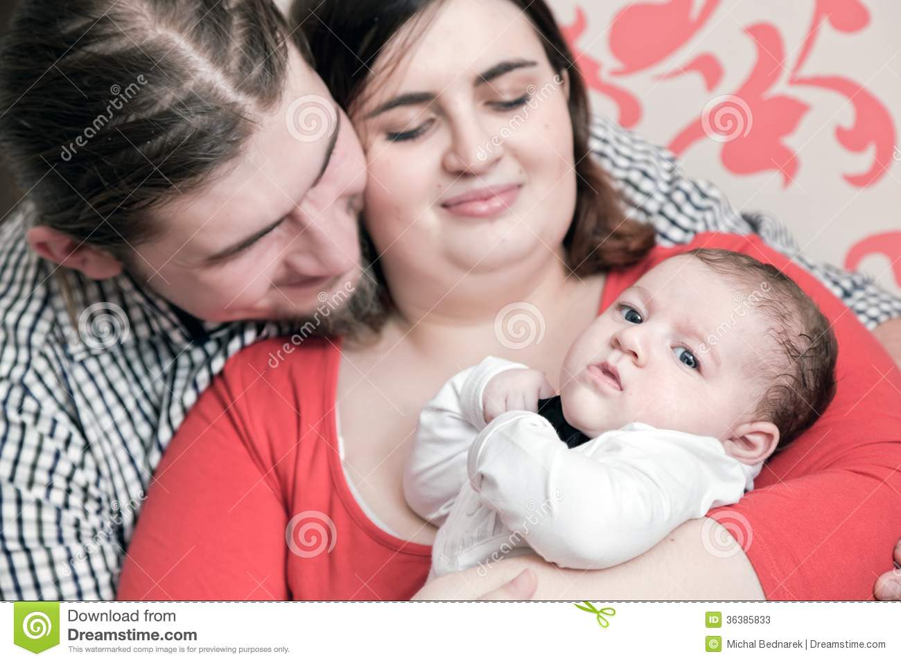     With Their Young Baby Cuddling Together  Happy Young Family Portrait