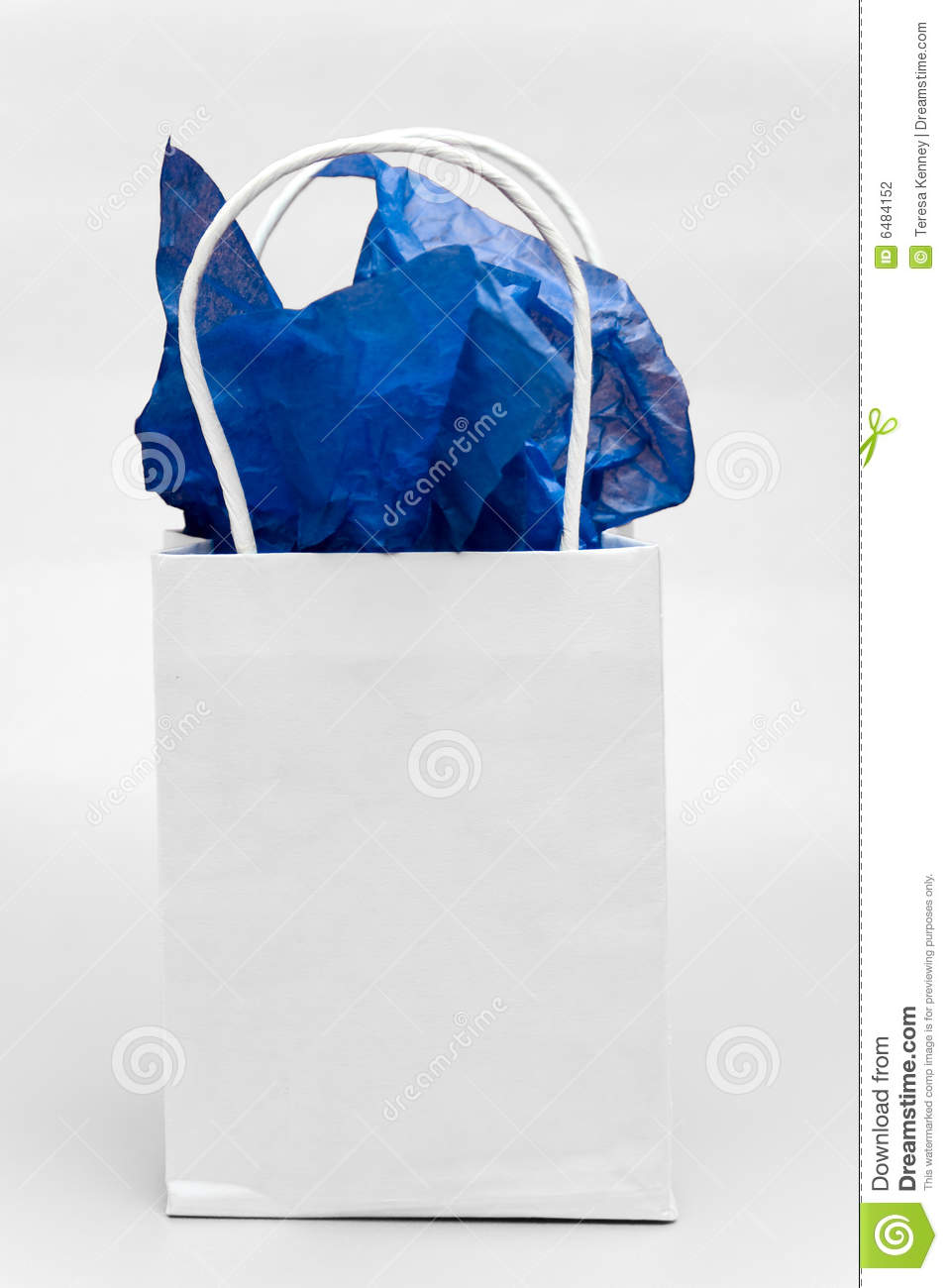 White Gift Bag With Blue Tissue Paper Against A Light Background 