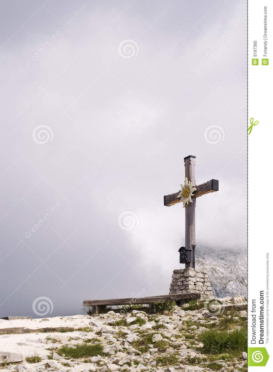 Cross Standing On A Mountain Peak With Clouds On The Background 